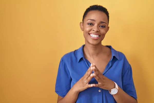 Sarı Arka Planda Dikilen Afro Amerikalı Kadın Ellerini Birleştirip Gülümseyerek — Stok fotoğraf