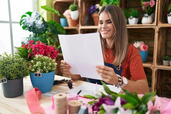 Young Beautiful Hispanic Woman Florist Reading Document Sitting Table Flower — ストック写真