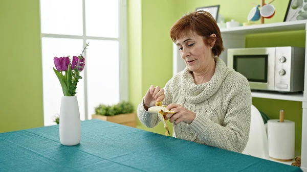 Mature Hispanic Woman Sitting Table Eating Banana Dinning Room — Stock Photo, Image