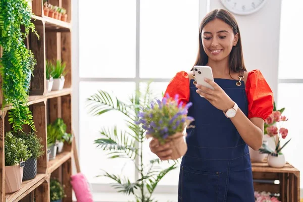 若い美しいヒスパニック系の女性の花屋は花屋でスマートフォンで植物に写真を撮る — ストック写真