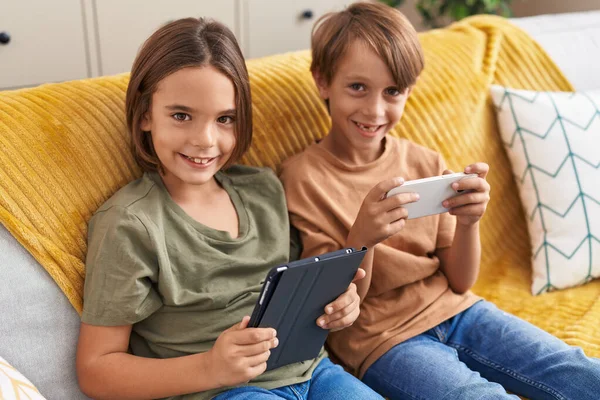 Akıllı Telefon Dokunmatik Ped Kullanan Sevimli Çocuklar Evdeki Kanepede Oturuyorlar — Stok fotoğraf