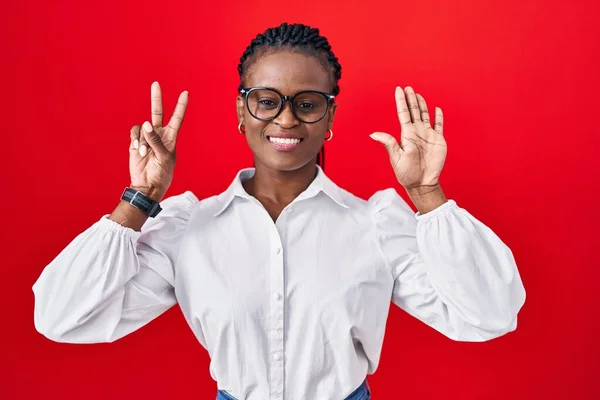 Afrikanerin Mit Zöpfen Steht Auf Rotem Hintergrund Und Zeigt Mit — Stockfoto