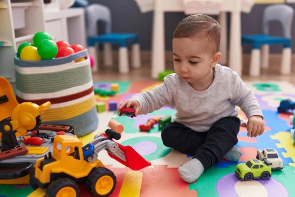 可敬的他的惊慌失措的儿子在幼儿园的地板上玩汽车玩具 — 图库照片
