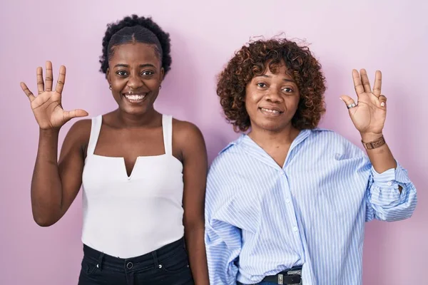 Dos Mujeres Africanas Pie Sobre Fondo Rosa Mostrando Señalando Hacia —  Fotos de Stock