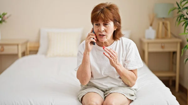 Μεσήλικη Γυναίκα Που Μιλάει Στο Smartphone Κάθεται Στο Κρεβάτι Και — Φωτογραφία Αρχείου