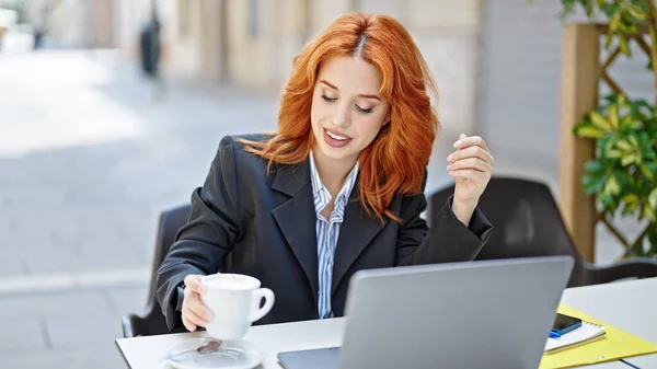 コーヒーショップのテラスでコーヒーのノートパソコンの保持カップを使用して若い赤毛の女性のビジネスワーカー — ストック写真