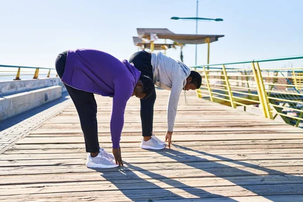 stock image Man and woman couple wearing sportswear stretching at seaside