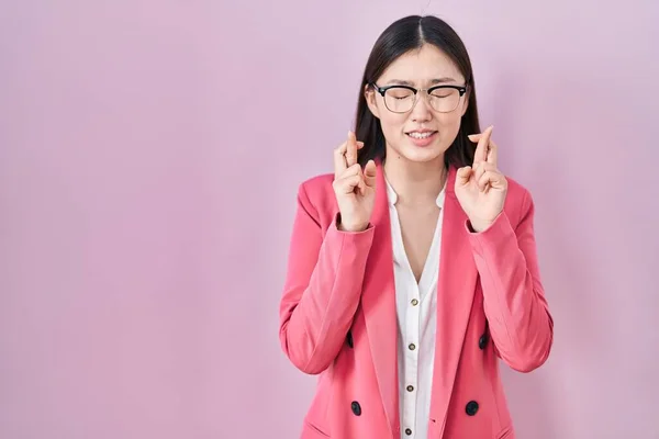 中国商界年轻女子戴着眼镜 摆弄着手指 满脸微笑 闭上了眼睛 幸运与迷信的概念 — 图库照片