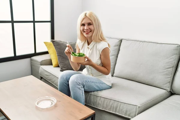 Mujer Rubia Joven Comiendo Ensalada Sentada Sofá Casa —  Fotos de Stock