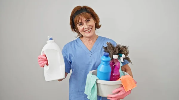 中年妇女专业清洁员将装有清洁用品和洗涤剂瓶的篮子放在孤立的白色背景上 — 图库照片