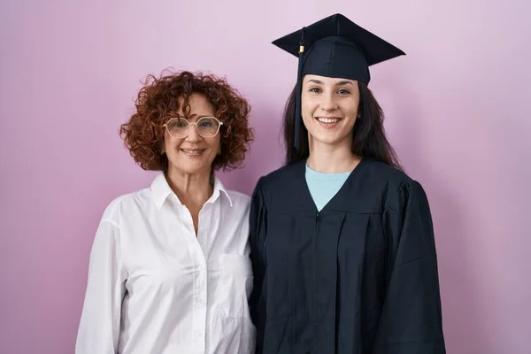 顔に幸せとクールな笑顔で卒業キャップと式のローブを身に着けているヒスパニック系の母親と娘 運のいい人 — ストック写真