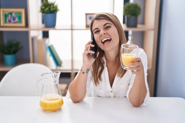 Mladá Žena Mluví Smartphone Pití Pomerančové Šťávy Doma — Stock fotografie