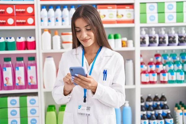年轻美丽的惊慌失措的女药剂师用智能手机在药店工作 — 图库照片
