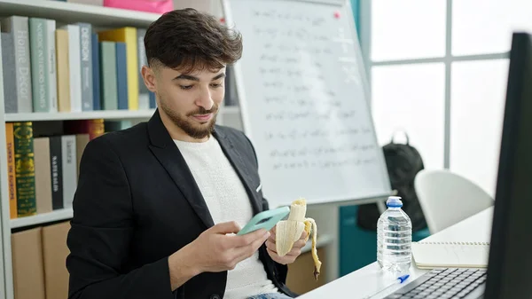 Tânăr Student Arab Folosind Smartphone Uri Care Mănâncă Banane Sala — Fotografie, imagine de stoc