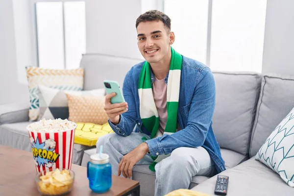 Young Hispanic Man Soccer Fan Using Smartphone Sitting Sofa Home — Stock Photo, Image