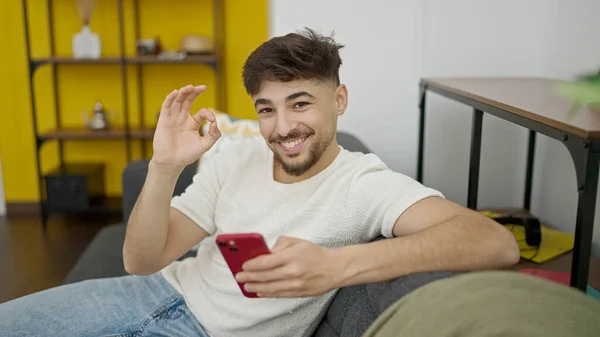 Νέοι Άραβας Άνθρωπος Χρησιμοποιώντας Smartphone Κάνει Εντάξει Χειρονομία Στο Σπίτι — Φωτογραφία Αρχείου
