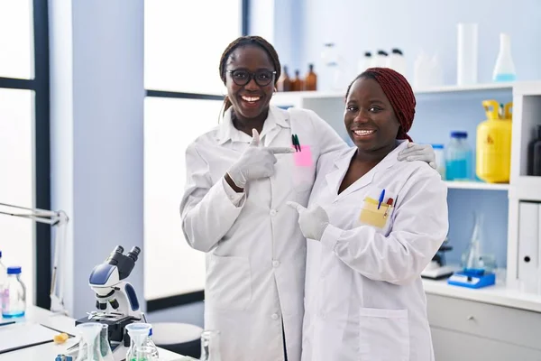 Dos Mujeres Africanas Trabajando Laboratorio Científico Sonriendo Felices Señalando Con —  Fotos de Stock