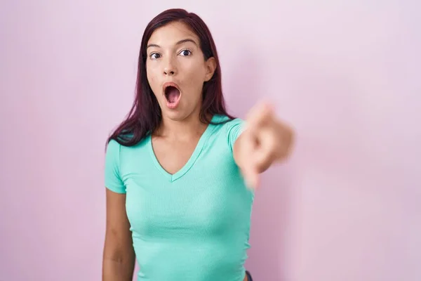 若いヒスパニック系の女性ピンクの背景の上に指を前に 口を開けて驚いて表現 何かが前に立っている — ストック写真