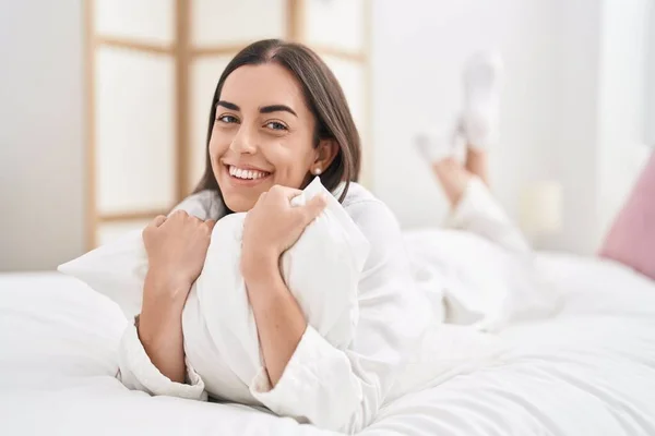 stock image Young hispanic woman hugging pillow lying on bed at bedroom