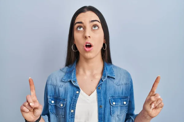 Hispanic Woman Standing Blue Background Amazed Surprised Looking Pointing Fingers — Foto Stock