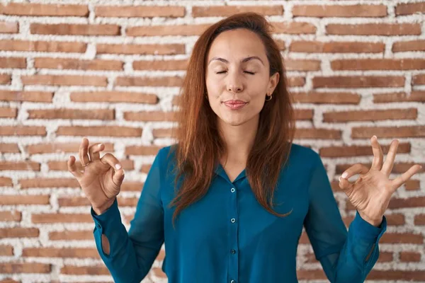站在砖墙上的布鲁内特女人放松了 闭上双眼微笑着 用手指做冥想动作 瑜伽概念 — 图库照片