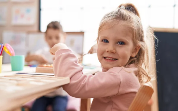 스러운 소녀는 유치원에서 테이블에 앉아서 자신있게 — 스톡 사진