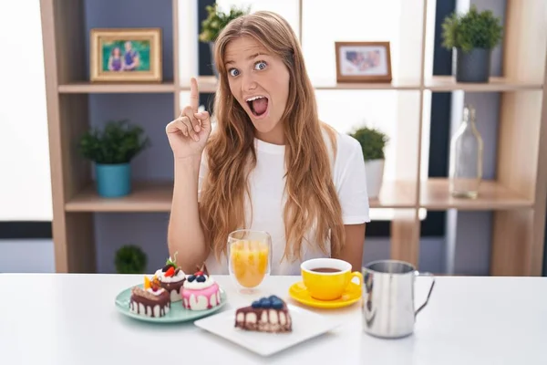 Joven Mujer Caucásica Comiendo Pasteles Para Desayuno Señalando Con Dedo —  Fotos de Stock