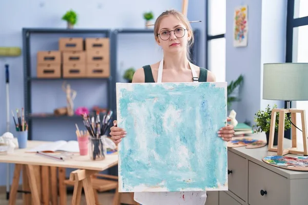 Young Caucasian Woman Holding Canvas Art Studio Relaxed Serious Expression — Stock Photo, Image