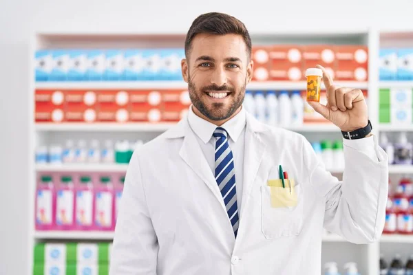 Handsome Hispanic Man Working Pharmacy Drugstore Holding Pills Looking Positive — Stock Photo, Image