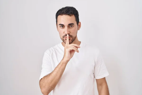 白い背景の上に立つハンサムなヒスパニック系の男が唇に指で静かにするように求めている 沈黙と秘密の概念 — ストック写真