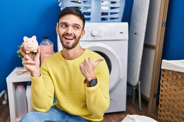 Hispanic Man Gör Tvätt Hålla Spargris Bank Pekar Tummen Upp — Stockfoto
