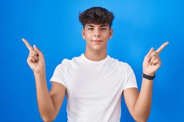 Іспаномовний Підліток Стоїть Над Синім Тлом Посміхаючись Впевнено Вказуючи Пальцями — стокове фото