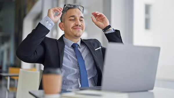 オフィスでメガネを取るラップトップを使用して若いヒスパニックの男のビジネスワーカー — ストック写真