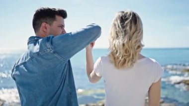 Kadın ve erkek deniz kenarında birbirlerine sarılıyorlar.