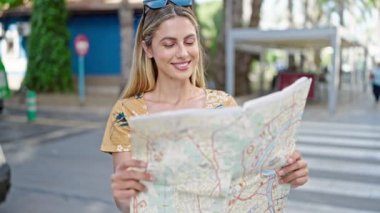 Genç sarışın kadın turist gülümsüyor. Kendine güvenen şehir haritası.