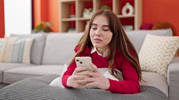 年轻的惊慌失措的女人用智能手机躺在家里沙发上 — 图库视频影像