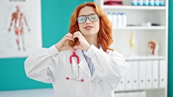 Jovem Ruiva Mulher Médico Sorrindo Fazendo Gesto Coração Com Mãos — Vídeo de Stock
