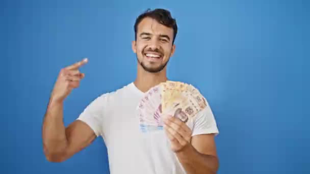 Ung Latinamerikansk Man Ler Säker Innehav Mexikanska Pesos Över Isolerad — Stockvideo