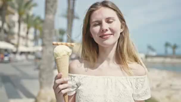 年轻的金发女游客笑着自信地在海滨拿着冰淇淋 — 图库视频影像