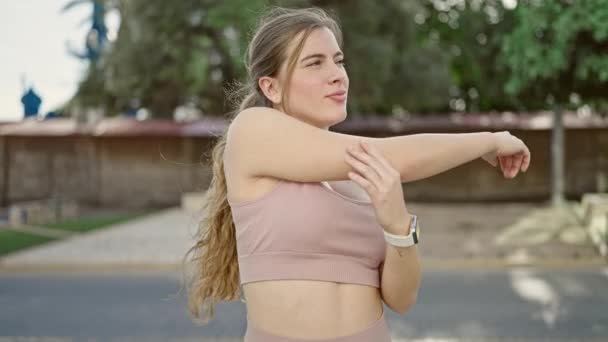 Spor Kıyafetleri Giyen Genç Sarışın Kadın Parkta Kollarını Esnetiyor — Stok video