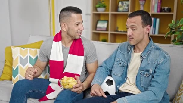 Δύο Άνδρες Που Υποστηρίζουν Την Ομάδα Ποδοσφαίρου Κάθεται Στον Καναπέ — Αρχείο Βίντεο