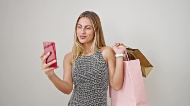 若いですブロンド女性保持ショッピングバッグ作る自画によってスマートフォン上の隔離された白い背景 — ストック動画