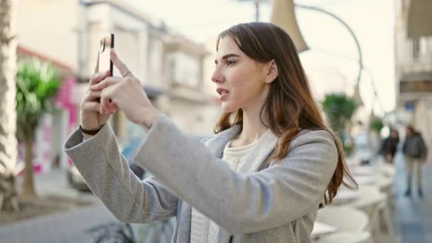 年轻的惊慌失措的女人用智能手机在咖啡店的阳台上微笑 — 图库视频影像