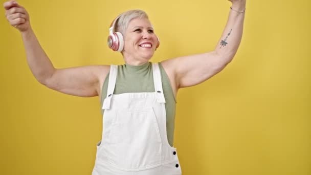 中年灰发女子在孤零零的黄色背景上微笑起舞 — 图库视频影像