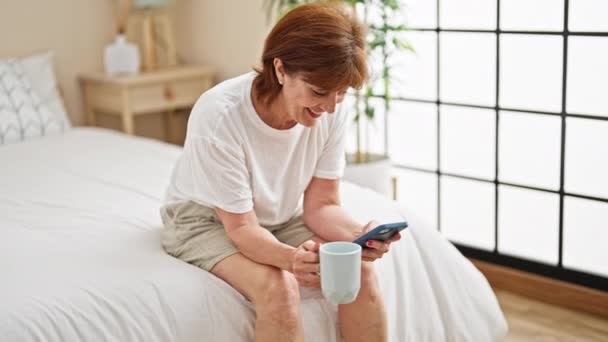 Mujer Mediana Edad Usando Teléfono Inteligente Beber Café Dormitorio — Vídeo de stock