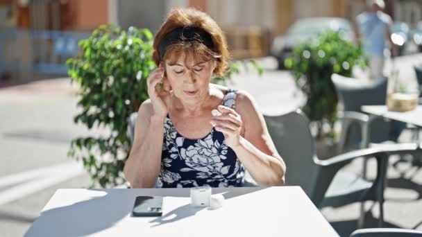 Mujer Mediana Edad Con Teléfono Inteligente Auriculares Sentados Mesa Terraza — Vídeos de Stock