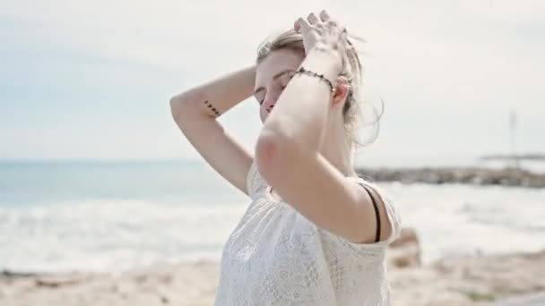 Młoda Blondynka Turystka Uśmiechnięta Pewnie Dotykając Włosów Plaży — Wideo stockowe