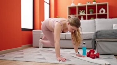Young blonde woman training core exercise at home