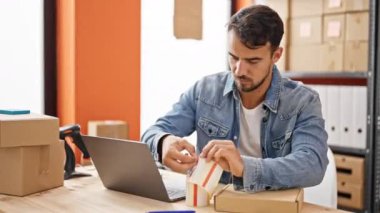 Latin kökenli genç bir iş adamı iş yerinde paket üzerine yazıyor.