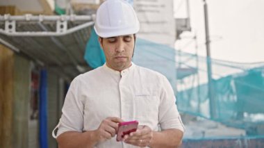 Genç İspanyol mimar sokakta akıllı telefon kullanıyor.